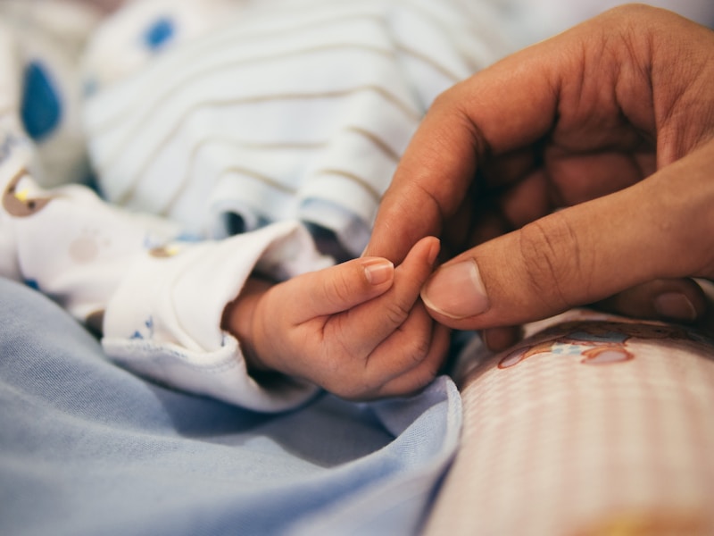 Adult holding baby hand - shared family tracker